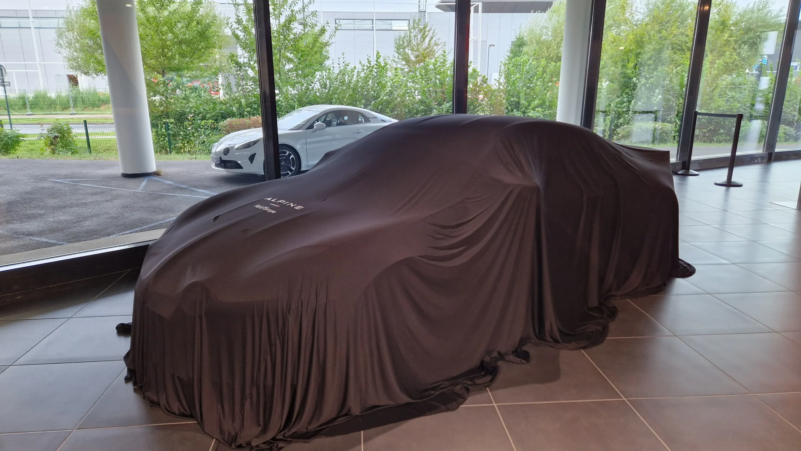 Véhicule Alpine sous drapé textile personnalisé dans un showroom concessionnaire